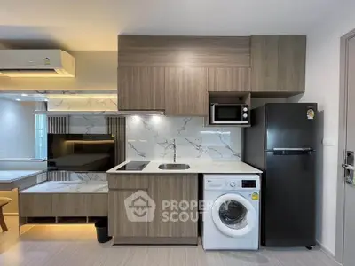 Modern kitchen with sleek cabinetry, washing machine, and fridge in stylish apartment.