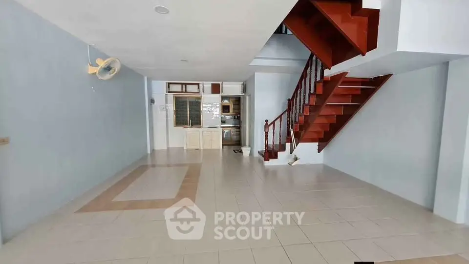 Spacious open-plan living area with staircase and kitchen in modern home.