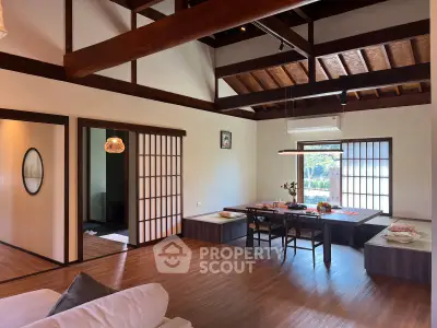 Spacious living room with wooden beams and traditional Japanese sliding doors, perfect for relaxation.