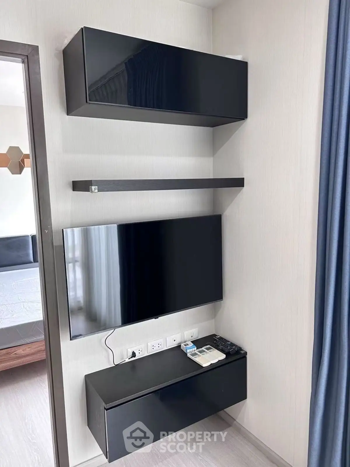 Modern living room with sleek black TV unit and wall-mounted shelves