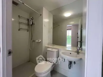 Modern bathroom with sleek fixtures and minimalist design, featuring a shower and toilet in a compact space.