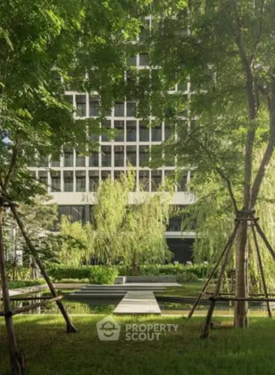 Luxurious building facade surrounded by lush greenery and serene garden pathway.