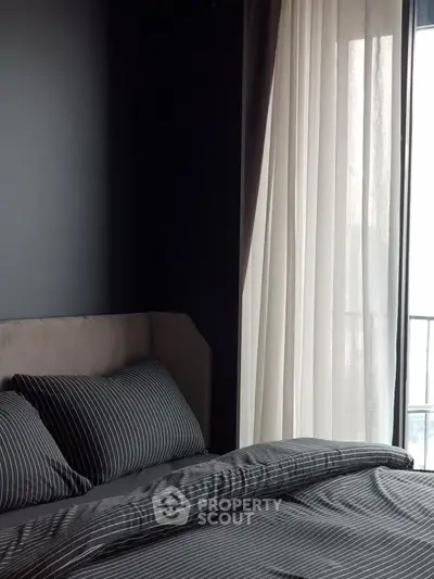 Modern bedroom with stylish dark walls and elegant striped bedding near a bright window.