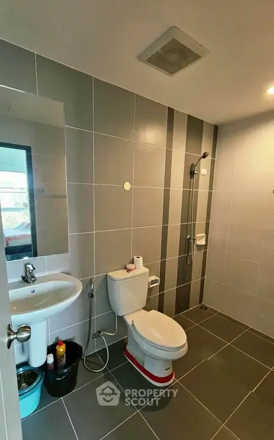 Modern bathroom with sleek gray tiles and contemporary fixtures in a stylish apartment.