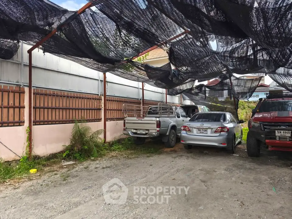 Spacious outdoor parking area with multiple vehicles under shade netting.