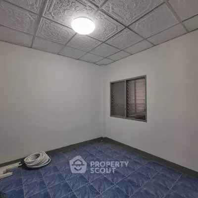 Spacious room with blue tiled floor and decorative ceiling, ideal for versatile use.
