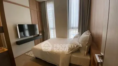Cozy modern bedroom with wall-mounted TV and large windows in a stylish apartment.