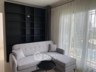 Modern living room with elegant sofa and large window offering natural light and city view.