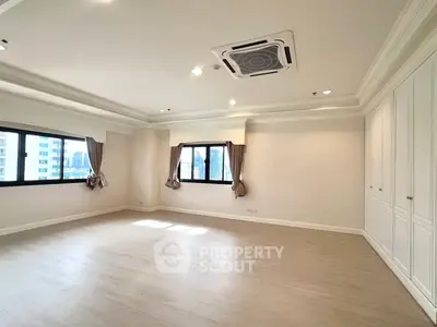 Spacious empty room with large windows and elegant ceiling design in modern apartment.