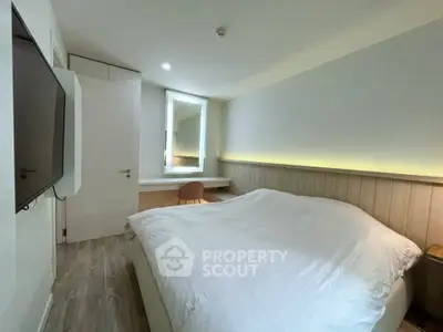 Cozy modern bedroom with sleek design and ambient lighting, featuring a wall-mounted TV and a stylish workspace.