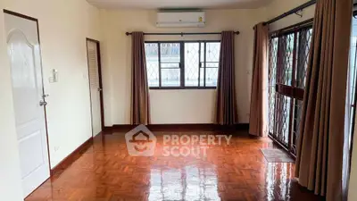 Spacious living room with polished wooden floors and large windows for natural light.
