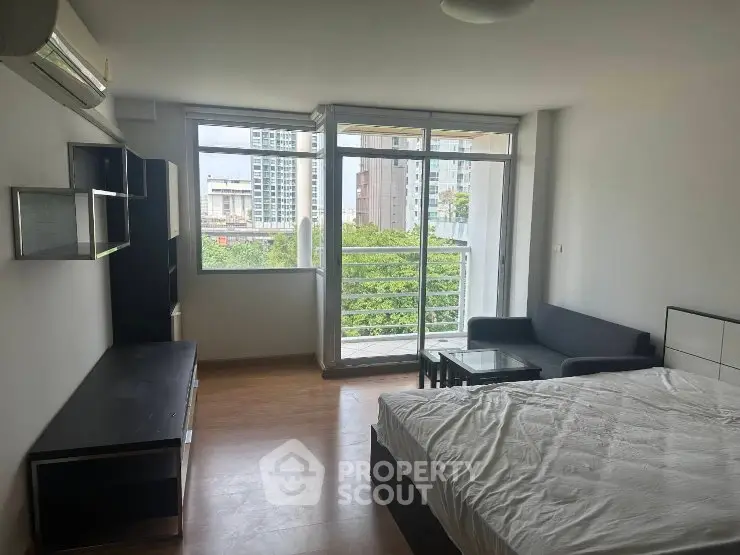 Spacious studio apartment with large windows and balcony view in modern urban setting.