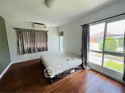 Spacious bedroom with large windows and hardwood floors in a modern home.