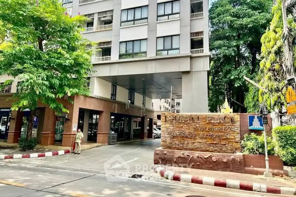Modern residential building entrance with lush greenery and clear signage, showcasing urban living.