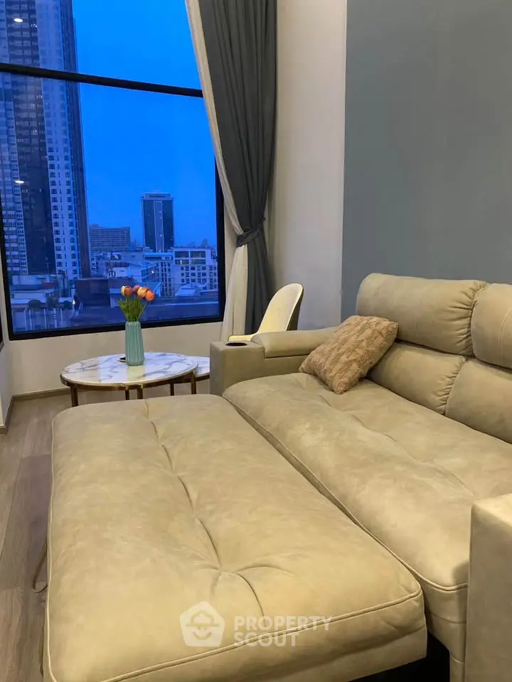 Luxurious living room with modern sofa and stunning city view through large window.