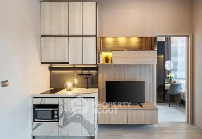 Modern kitchen with marble cabinets and sleek TV setup in stylish apartment.