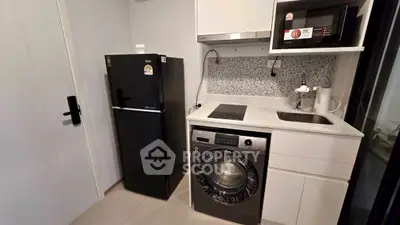 Modern compact kitchen with fridge, washing machine, and microwave in sleek design.