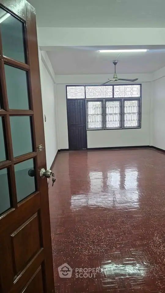 Spacious empty room with polished wooden floor and large windows, perfect for customization.