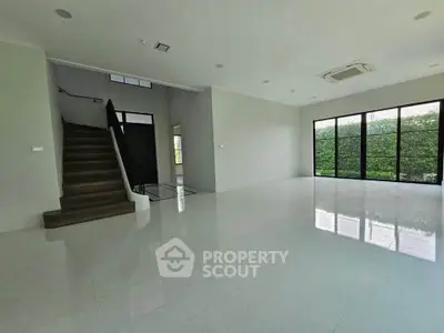 Spacious modern living room with large windows and staircase, perfect for family gatherings.
