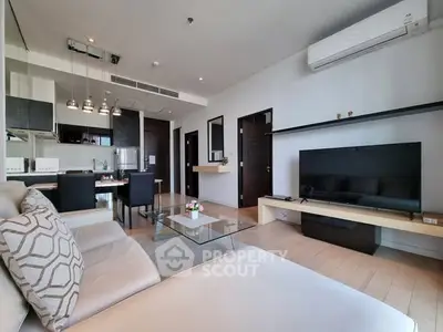 Modern living room with open kitchen, sleek furniture, and large TV in a stylish apartment.