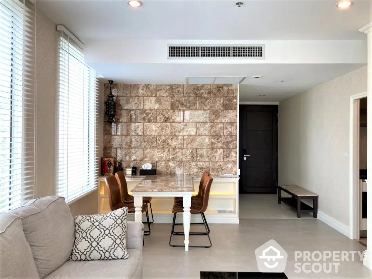 Elegant open-plan living space with modern kitchen, marble feature wall, and ample natural light, perfect for entertaining and relaxation.