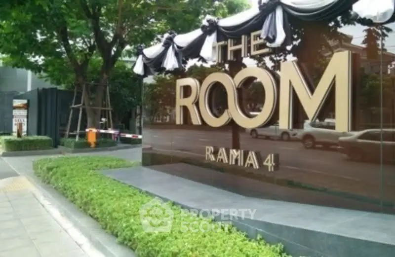 Luxurious entrance of The Room Rama 4 with elegant signage and lush greenery.