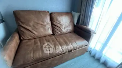 Luxurious leather sofa in a bright living room with floor-to-ceiling windows.