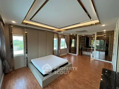 Spacious modern bedroom with elegant ceiling design and large windows offering scenic views.