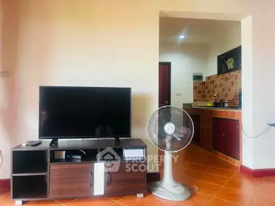 Cozy living room with TV, fan, and open kitchen layout in modern apartment.