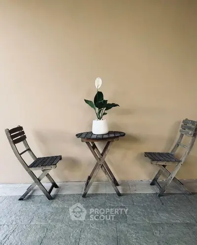 Charming outdoor patio with rustic wooden furniture and potted plant.