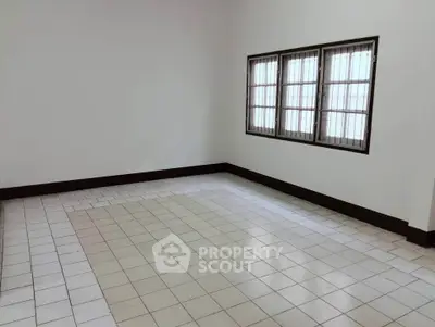 Spacious empty room with tiled flooring and large windows, perfect for customization.