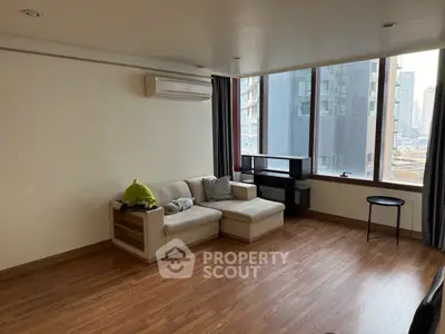 Spacious living room with large windows and modern furniture in urban apartment