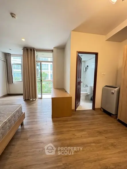 Spacious bedroom with wooden flooring and balcony access in modern apartment