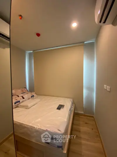 Cozy bedroom with modern design and natural lighting, featuring a comfortable bed and sleek air conditioning unit.