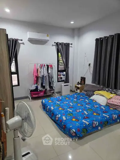 Cozy bedroom with colorful bedding and modern decor, featuring air conditioning and ample natural light.