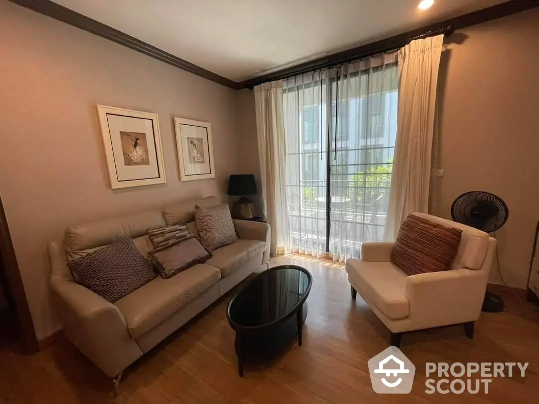 Elegant living room with plush seating, hardwood floors, and ample natural light streaming through sheer curtains, perfect for relaxation and entertaining guests.