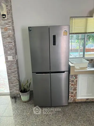 Modern kitchen with sleek stainless steel refrigerator and stylish stone backsplash.