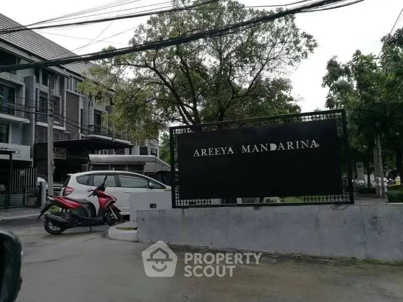 Modern residential building with lush greenery at Areeya Mandarina entrance.