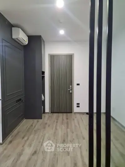 Modern apartment entrance with sleek wooden flooring and air conditioning unit.