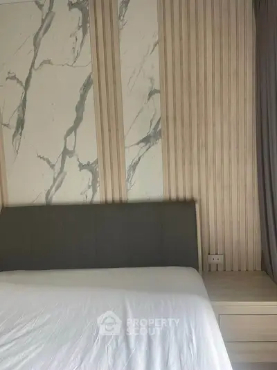 Modern bedroom with elegant marble accent wall and cozy bed setup.