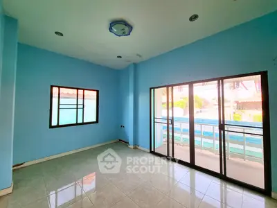 Spacious room with blue walls and large windows offering natural light and outdoor view.