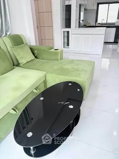 Modern living room with green sofa and sleek black coffee table in open-plan layout.