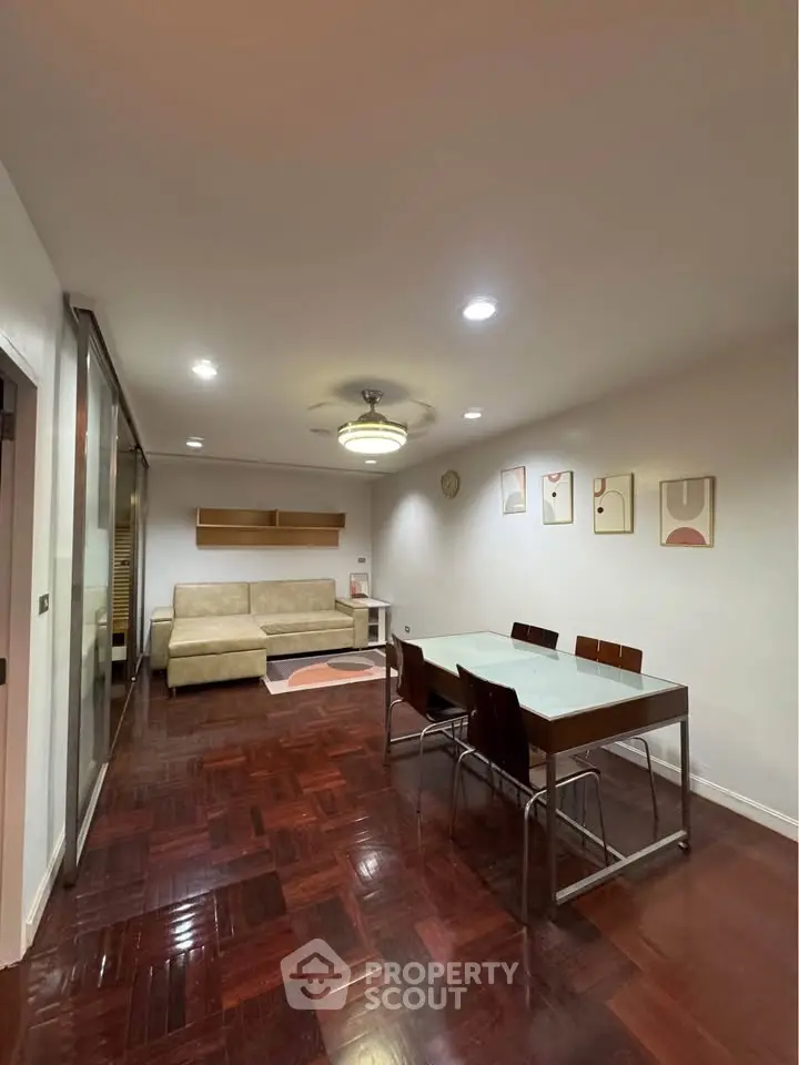 Spacious living room with modern decor and wooden flooring, featuring a dining area and cozy seating.
