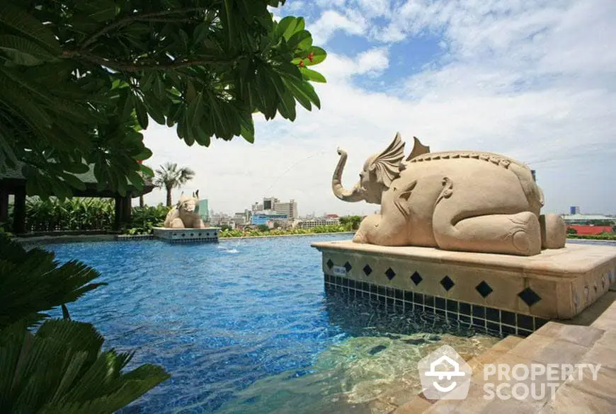 Luxurious resort-style pool with an impressive elephant sculpture, surrounded by lush greenery and a serene ambiance, perfect for high-end real estate listings.