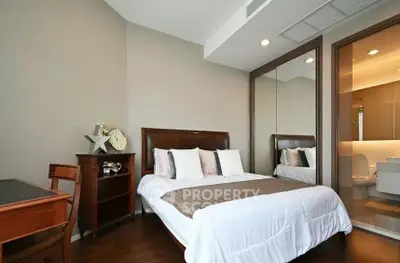 Elegant bedroom with wooden furniture and ensuite bathroom in modern apartment.