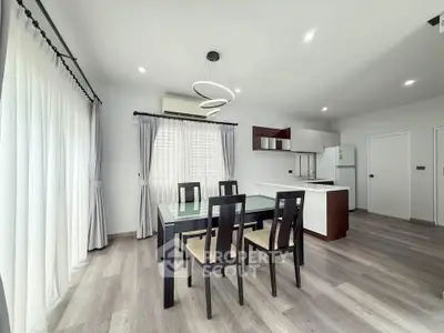 Modern dining area with sleek furniture and open kitchen layout in a bright, airy apartment.