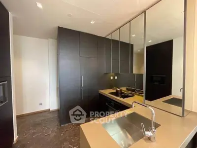 Modern kitchen with sleek cabinetry and built-in appliances, featuring a stylish sink and mirrored backsplash.