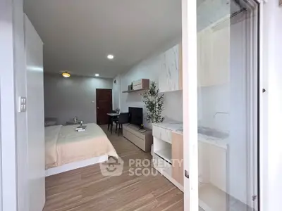 Modern studio apartment with open layout, featuring a cozy bed, sleek kitchen, and stylish living area.