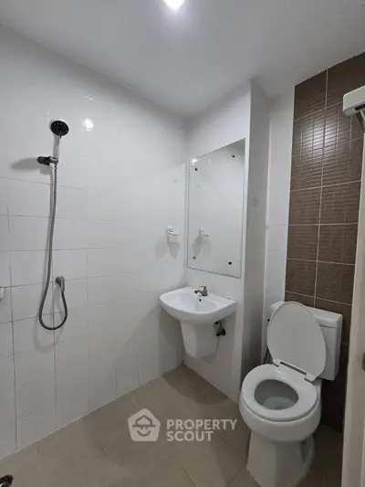 Modern bathroom with shower, sink, and toilet in a sleek, tiled design.