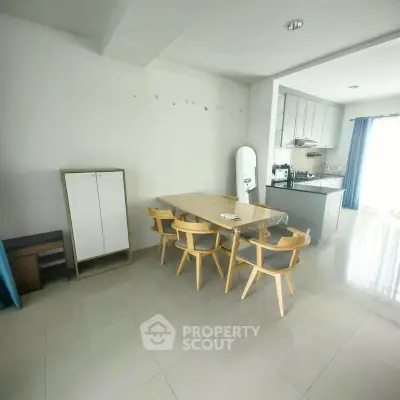Modern dining area with sleek kitchen in open layout, featuring natural light and minimalist design.